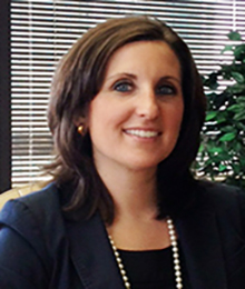 Alexandria Hill Alexandria Hill, Caucasian female with brown hair, wearing a navy blazer and pearl necklace, pictured in an office setting in front of a window