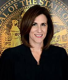 Honorable Lisa Walsh Honorable Lisa Walsh headshot, Caucasian female with short dark brown hair is pictured in front of a government seal