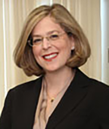 Julie Braman Kane Julie Braman Kane headshot, Caucasian businesswoman is smiling, wearing a black suit and glasses