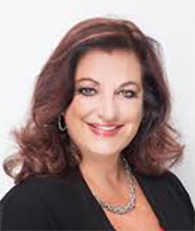 Mayanne Downs Mayanne Downs headshot, Caucasian woman dressed in a black business top, she has brown hair and is pictured in front of a white background